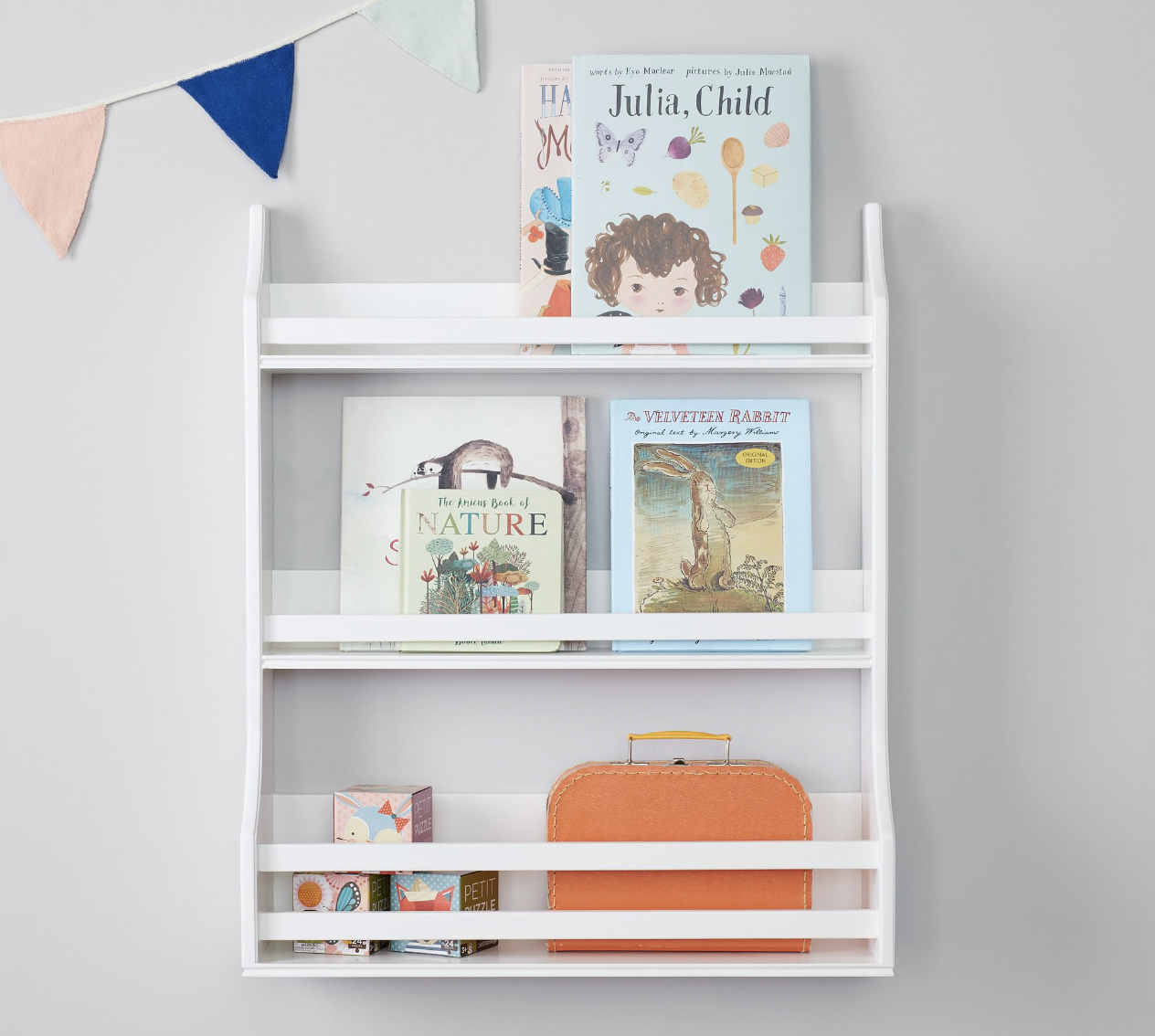 Wall-mounted, three-tier bookrack holding children's books in a nursery.